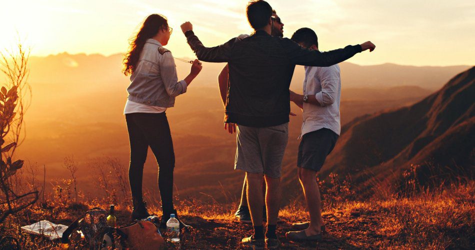 four person standing at top of grassy mountain