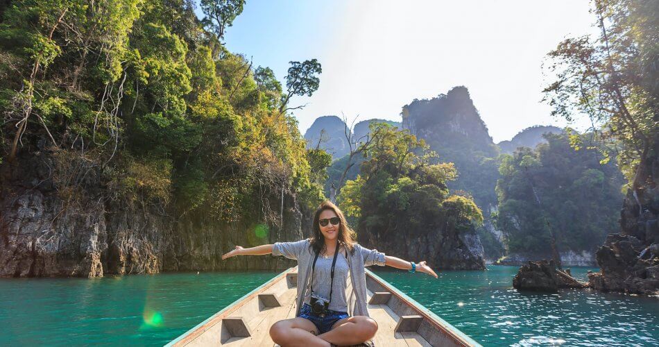 photo of woman sitting on boat spreading her arms