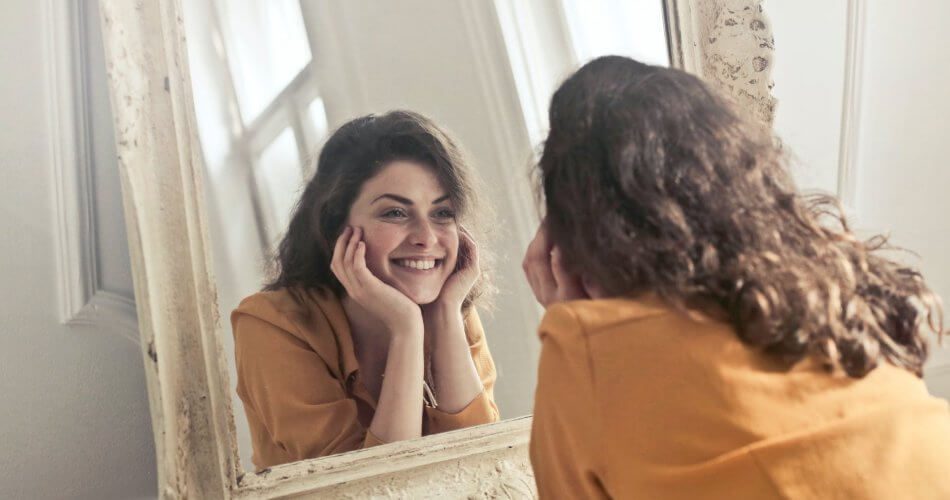 photo of woman looking at the mirror