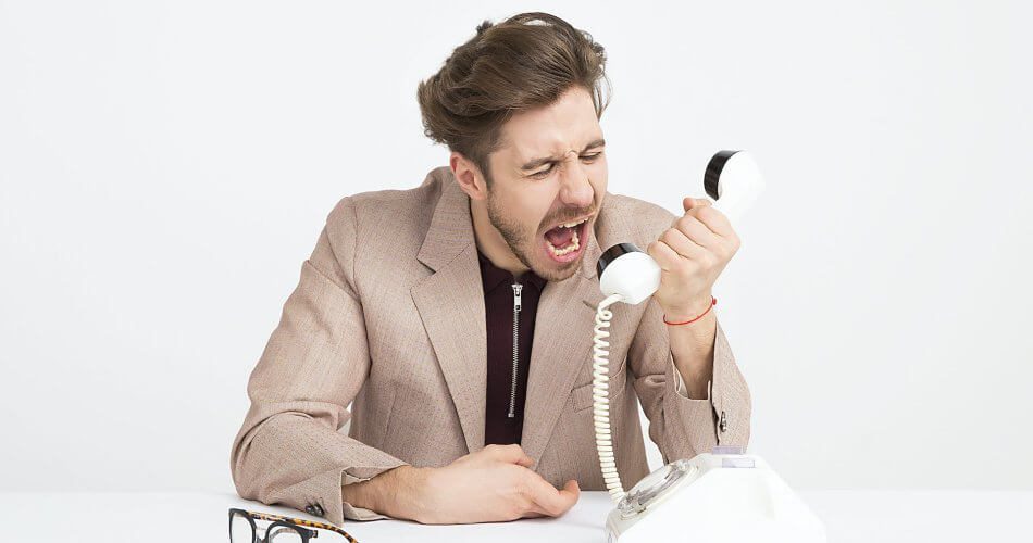 man wearing brown suit jacket mocking on white telephone
