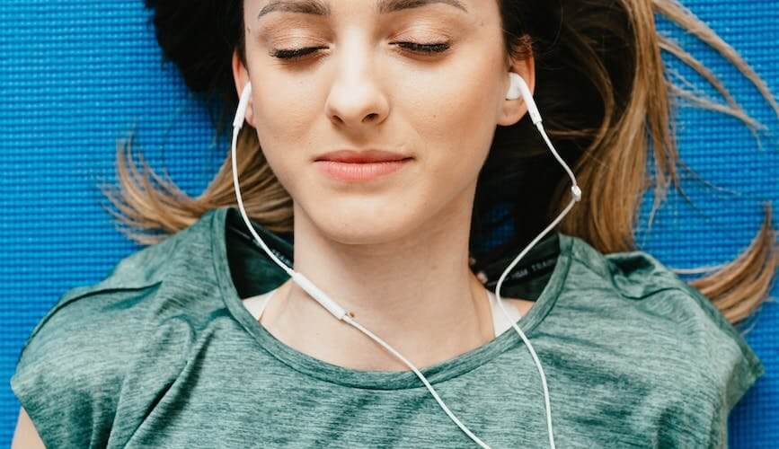 young woman listening to music in earphones in apartment